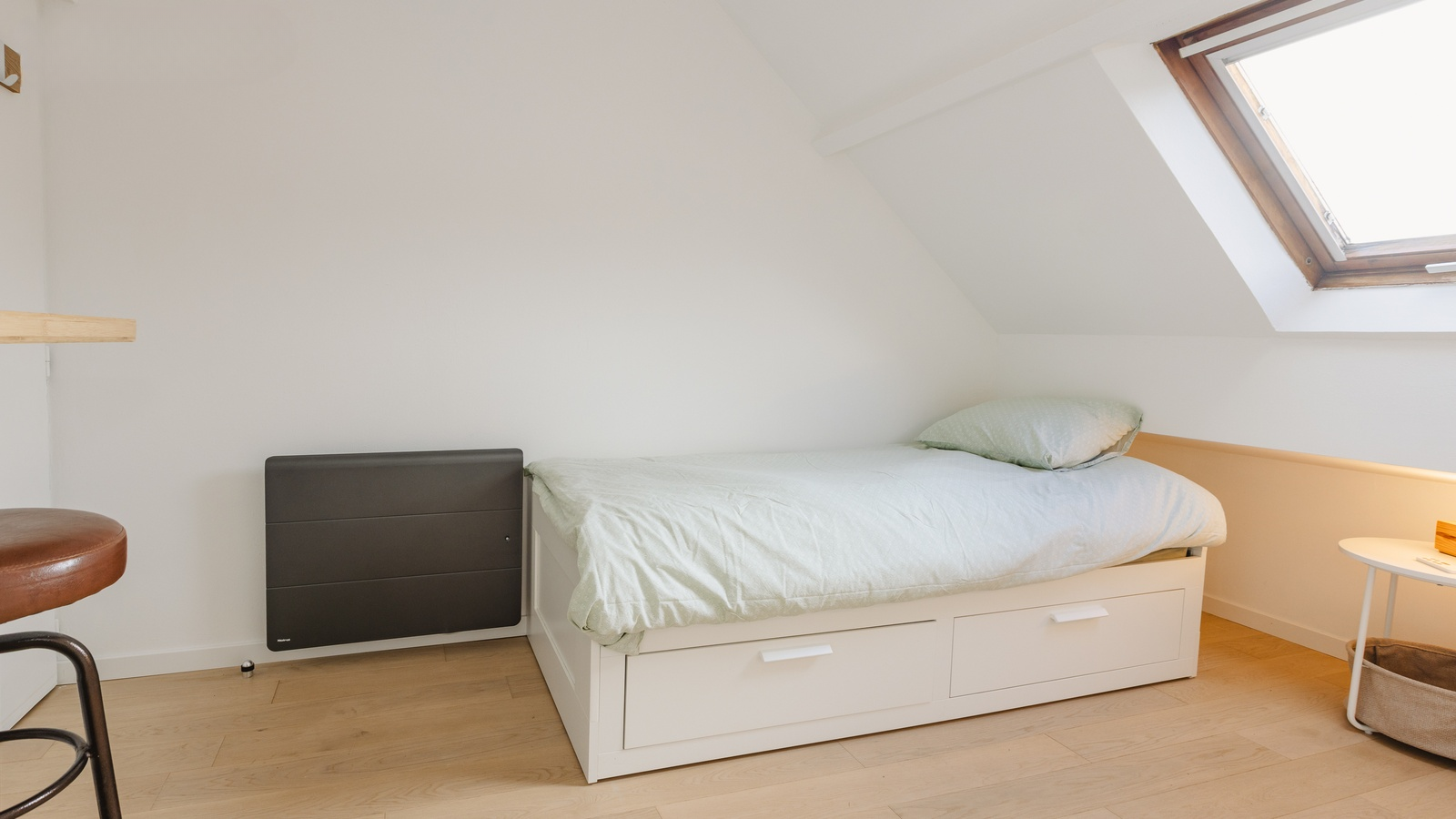 Le lit avec ses tiroirs de rangement et le radiateur